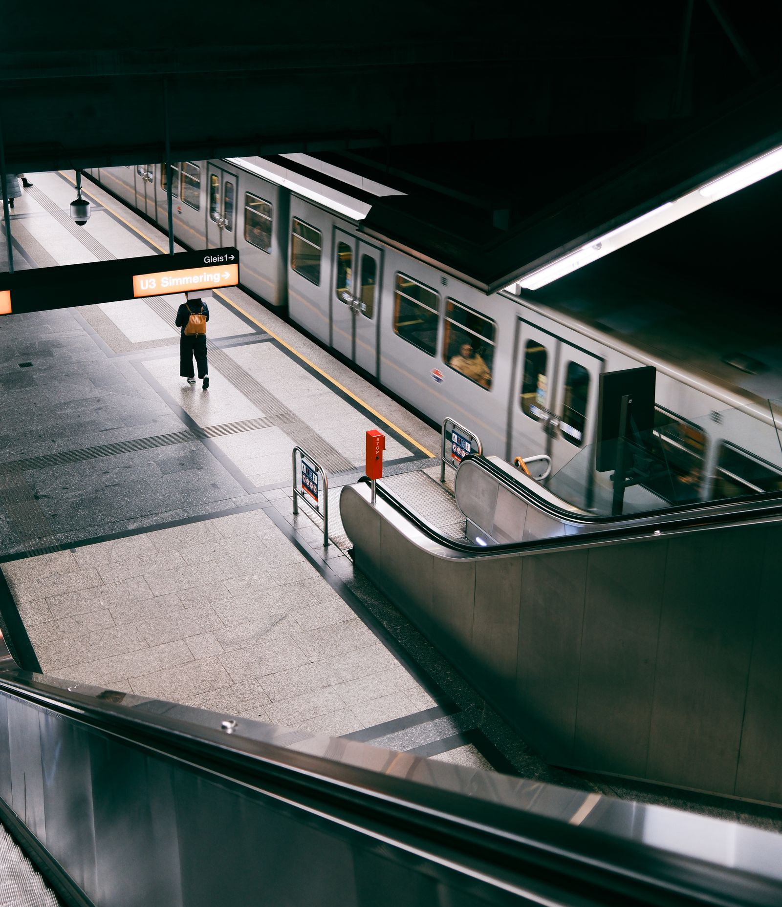 Busy metro station with escalators and an arriving train