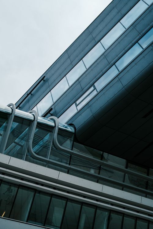 Free Dynamic angle view of a modern glass building showcasing sleek lines and contemporary design. Stock Photo
