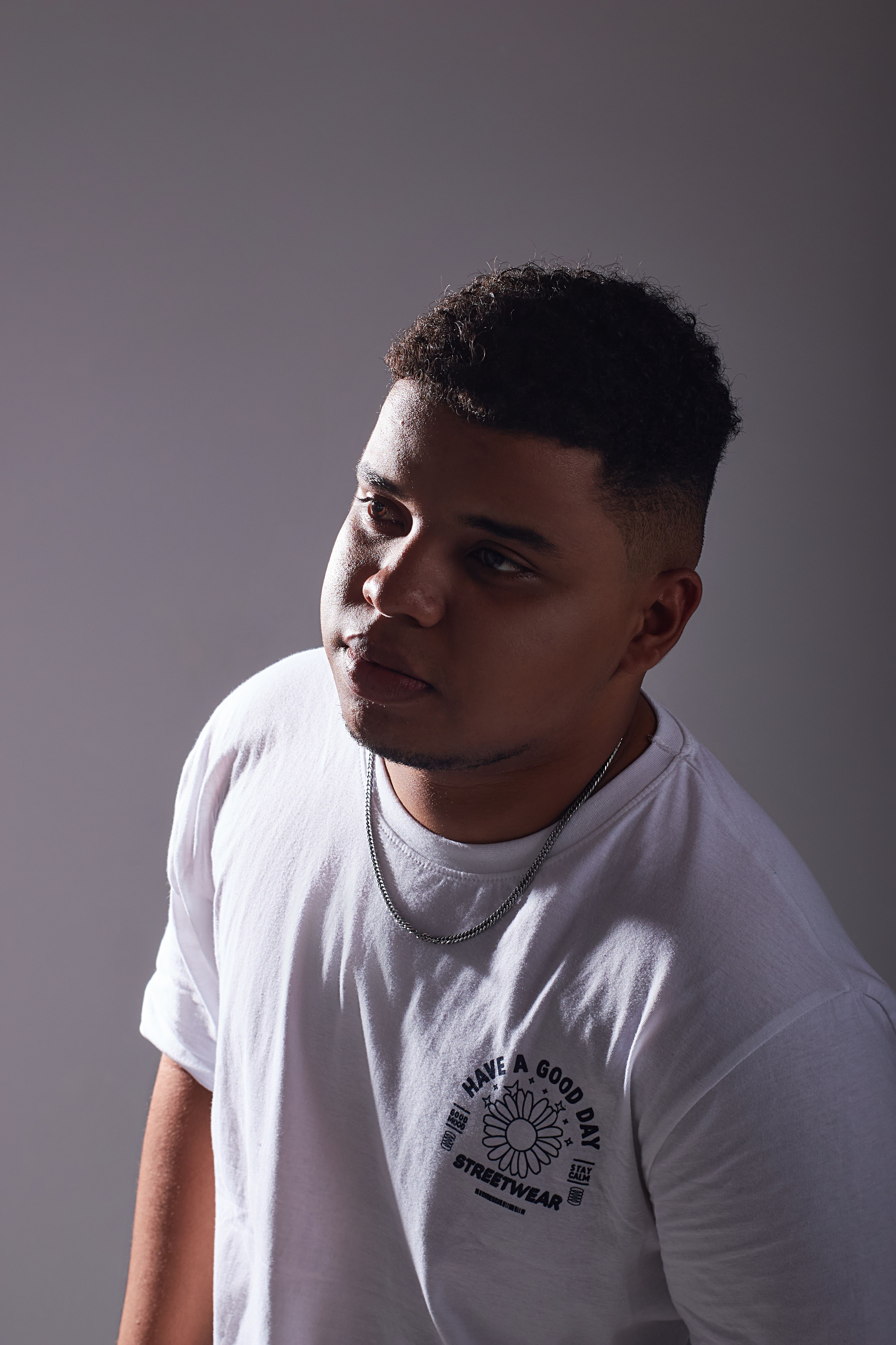 Introspective portrait of a young man in a white shirt, thoughtful pose.