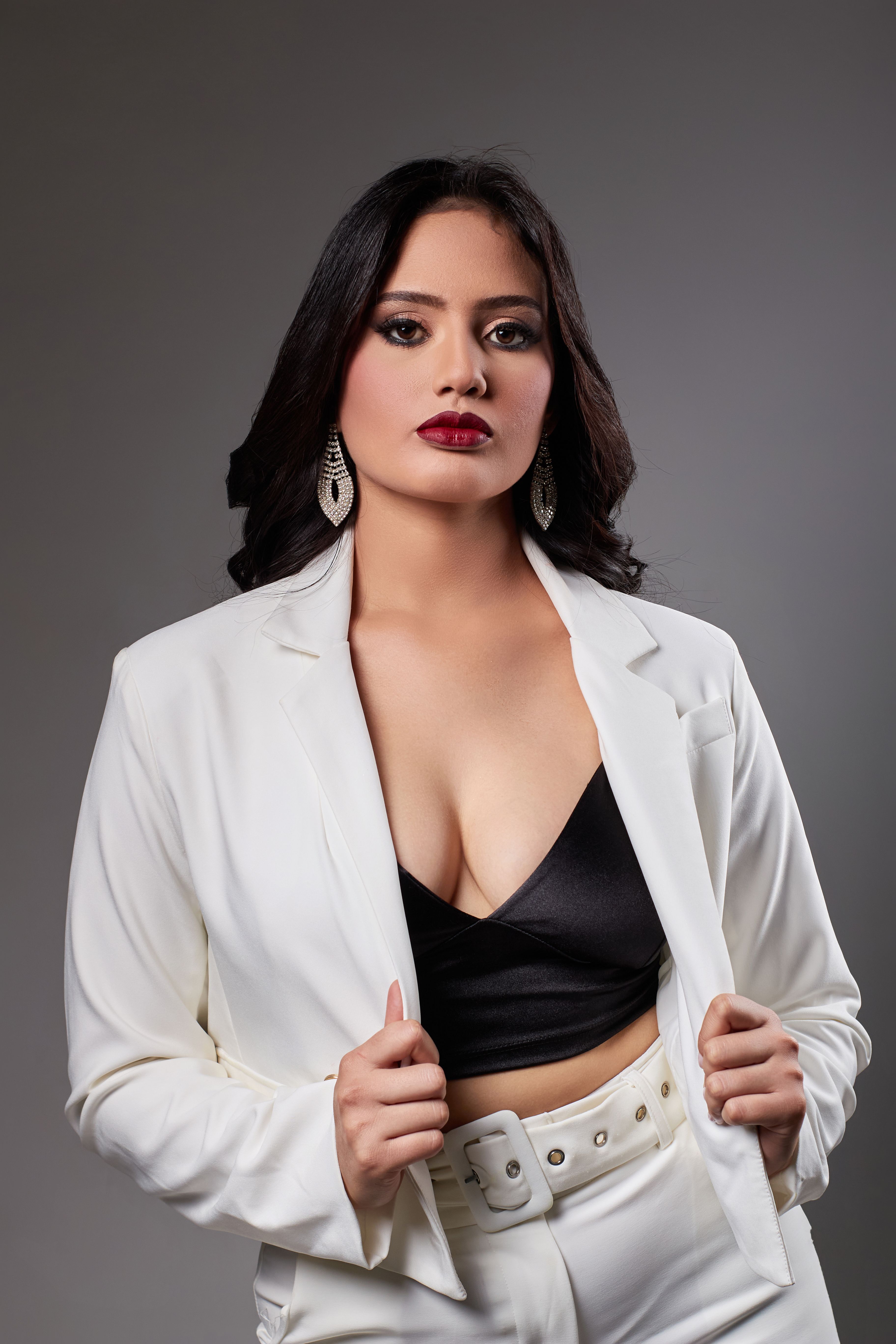 Stylish woman in a white suit with red lipstick posing confidently.