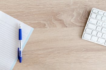 Blue Retractable Pen on Top of Notebook Near Magic Keyboard