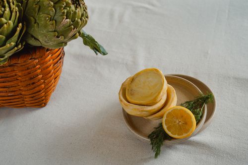 Free A cozy and rustic still life with artichokes and lemons on a woven basket and plate. Stock Photo