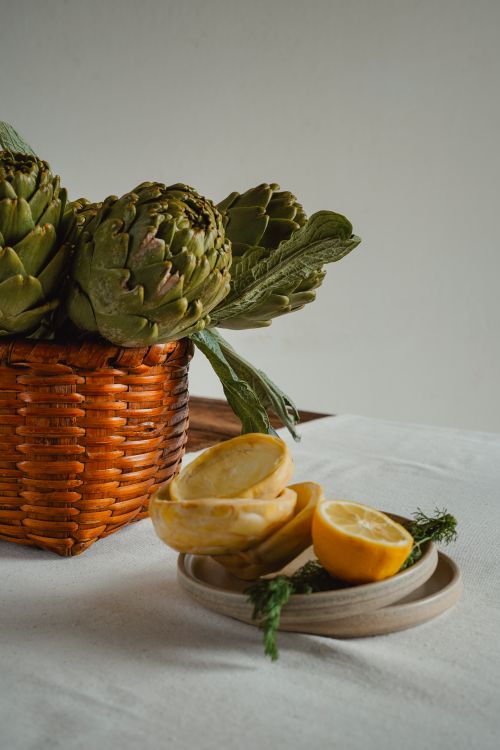 Free A basket of artichokes and sliced lemons on a plate creating a rustic, earthy kitchen ambiance. Stock Photo