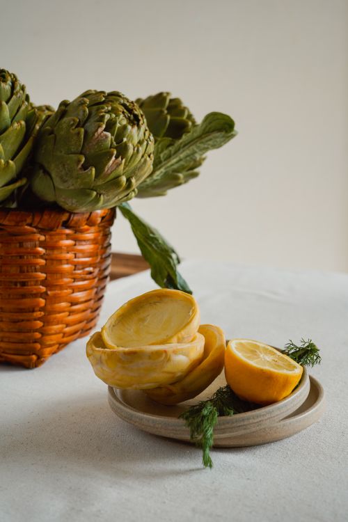 Free A rustic still life featuring fresh artichokes and sliced lemons, creating a vibrant and earthy kitchen scene. Stock Photo