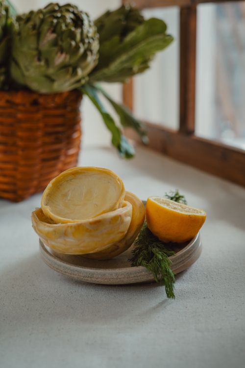 Free A cozy kitchen scene featuring artichokes, lemon halves, and pastry shells on a table by the window. Stock Photo