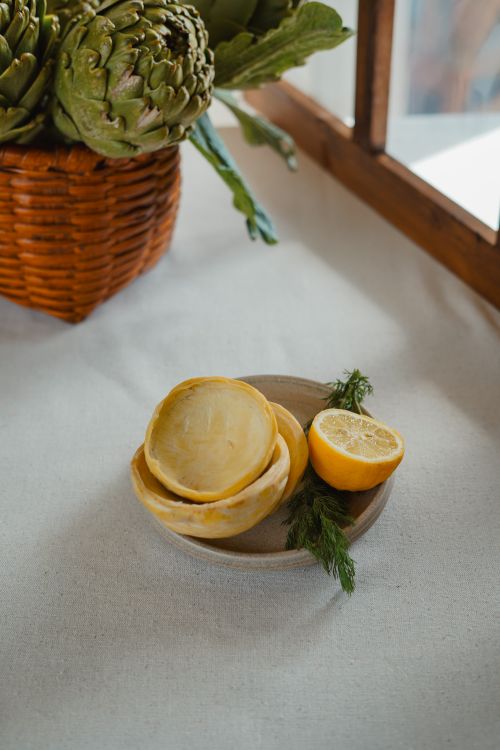 Free Fresh artichokes in a basket and lemons on a table, perfect for culinary themes. Stock Photo