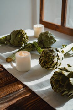 A rustic table with artichokes and candles, creating a warm, inviting scene.