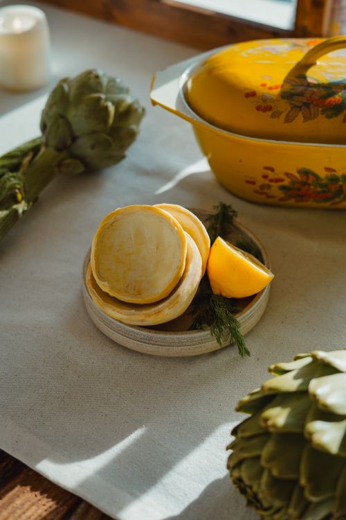 Free Artichoke and sliced radish with lemon on a rustic tabletop setting. Stock Photo