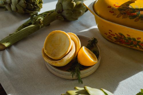 Free Close-up of artichokes and sliced lemon on a rustic table setting with vintage cookware. Stock Photo