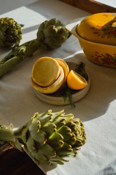 Artistic arrangement of fresh artichokes and lemons in warm sunlight.