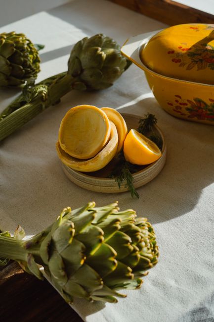 Artistic arrangement of fresh artichokes and lemons in warm sunlight.