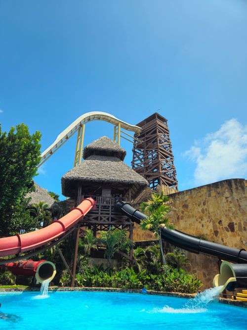Free Colorful water slides tower over a lush tropical adventure park, inviting thrill-seekers. Stock Photo