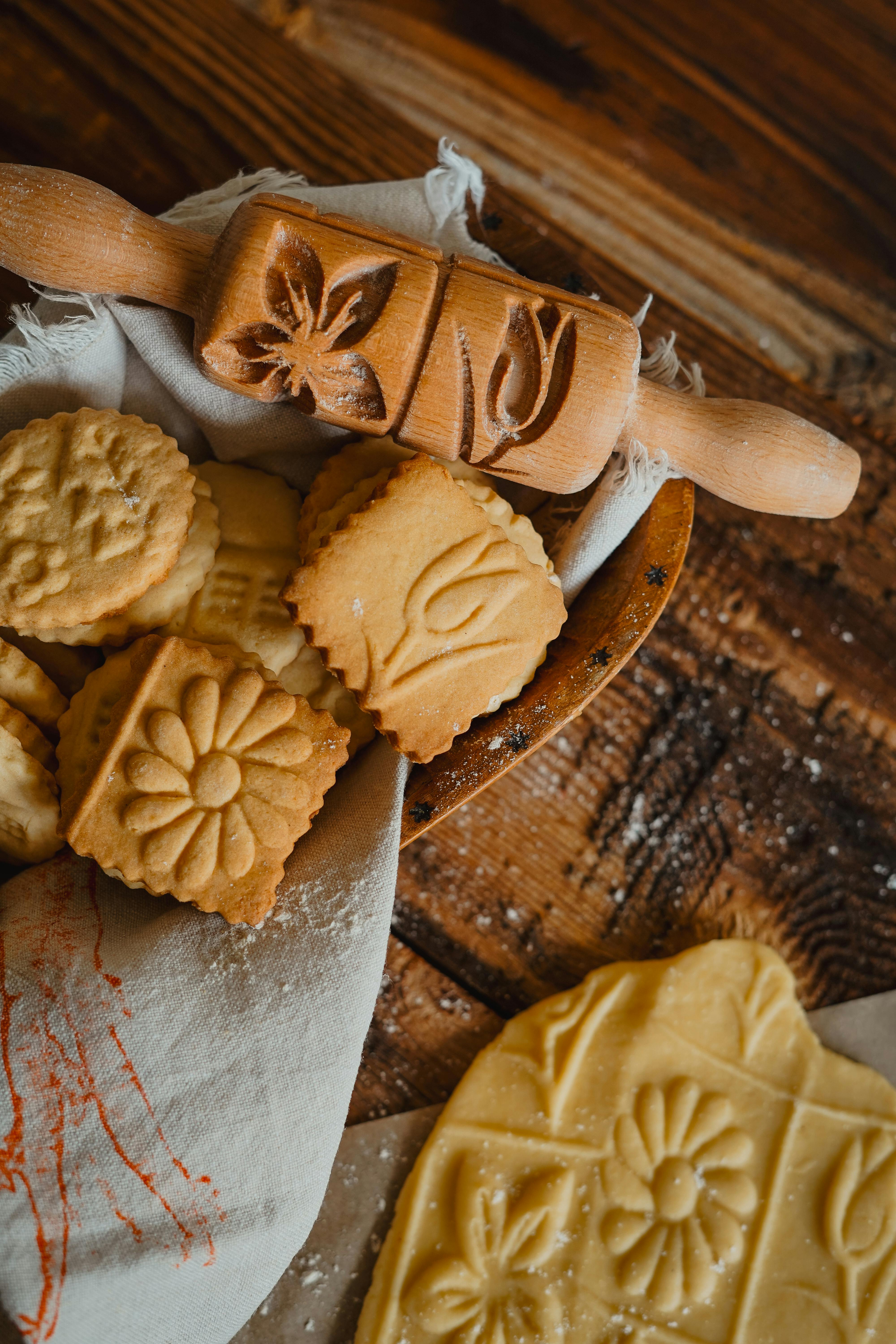 Homemade cookies on a rustic table with an engraved rolling pin, ideal for baking enthusiasts.