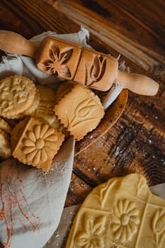 Homemade cookies on a rustic table with an engraved rolling pin, ideal for baking enthusiasts.