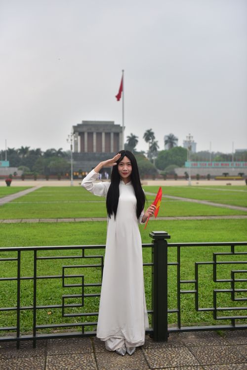 Free Woman in white traditional dress saluting near Ho Chi Minh Mausoleum in Hanoi. Stock Photo