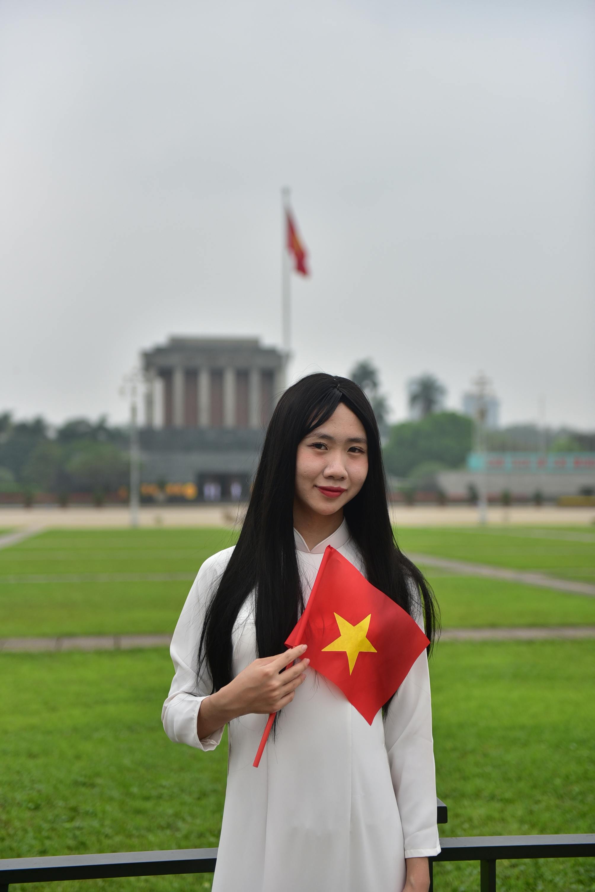 A woman holds a Vietnam flag in front of a significant landmark, creating a sense of national pride.