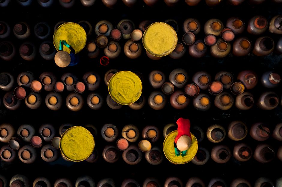 Top-down view of workers arranging traditional pottery, showcasing cultural craftsmanship.