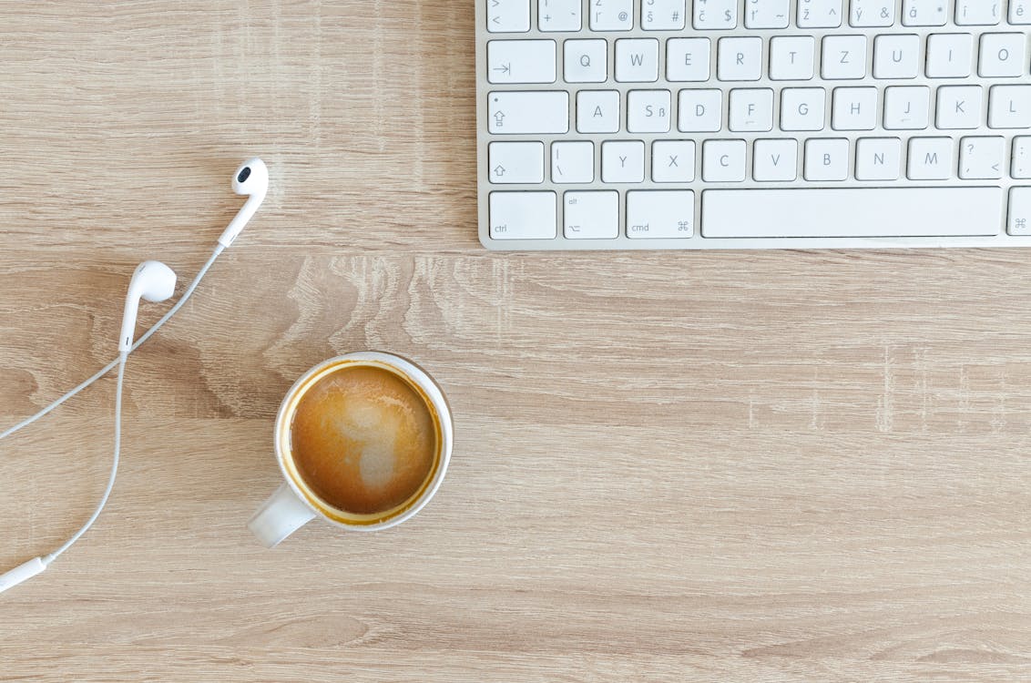 Beverage Filled Mug Near Apple Airpods With Lightning Connector and Apple Magic Keyboard