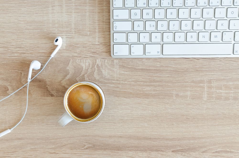 キーボードとコーヒー、イヤホンが置かれた学習デスク