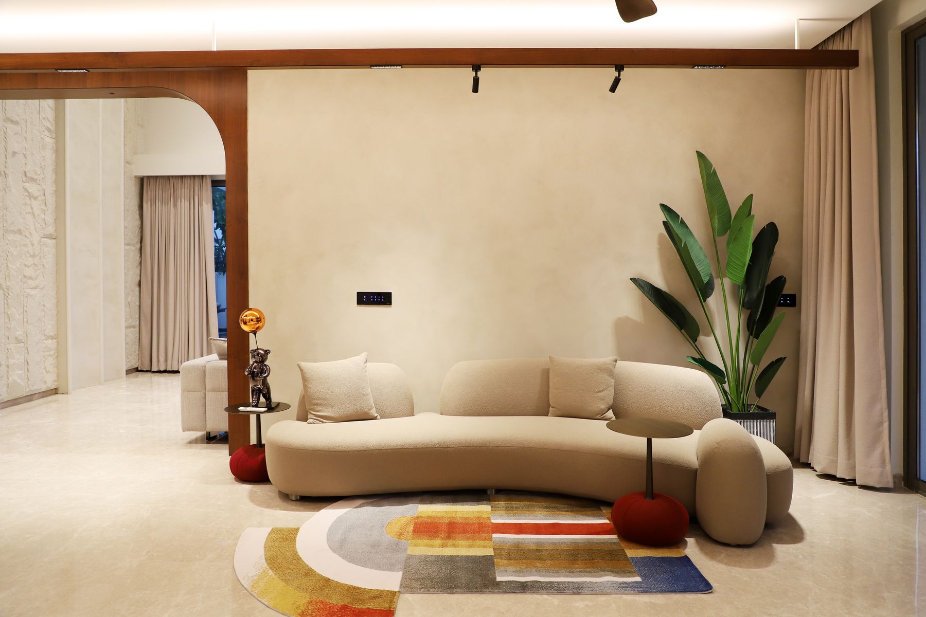 Contemporary apartment living room with a curved sofa, patterned rug and sculptural furniture
