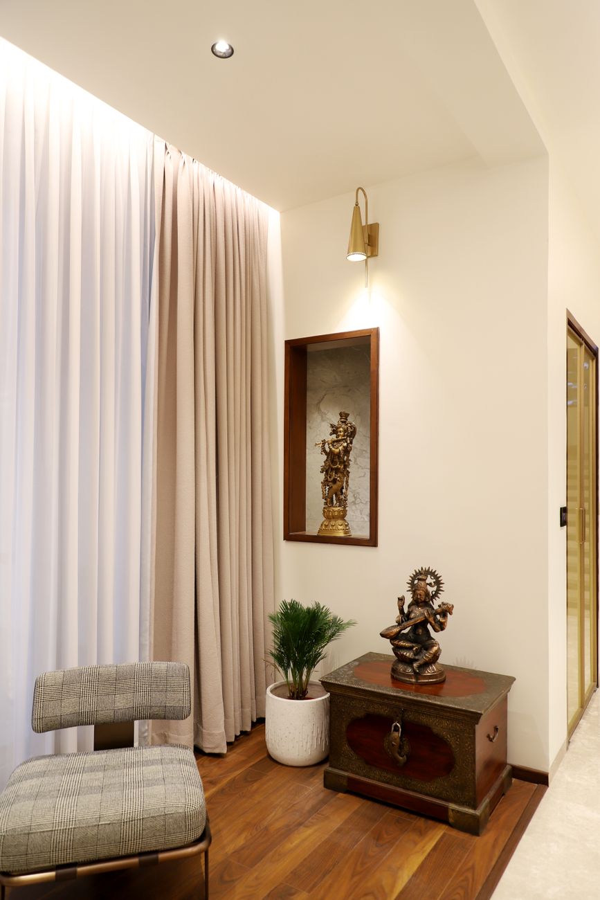 A cozy interior corner featuring a stylish chair, decor chest, and a statue under warm lighting.