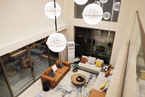 Free Spacious living room with modern decor and large windows, featuring elegant lighting and comfortable seating arrangements. Stock Photo