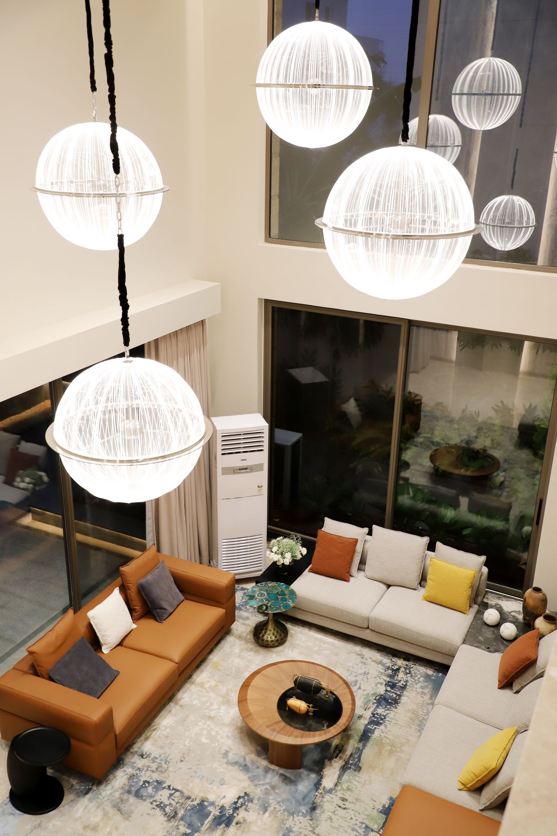 Spherical pendant lights hanging through a tall contemporary apartment living space