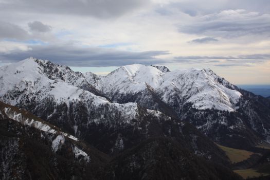 Breathtaking view of snow-covered mountains under a cloudy sky, capturing the essence of winter.