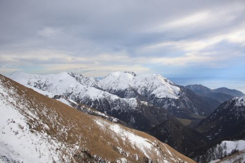 Free Panoramic view of a snow-covered mountain range with a cloudy sky backdrop. Stock Photo