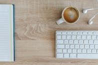 工作空间很平整，木桌上放着咖啡、键盘和笔记本