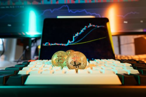 Free Close-up of Bitcoin coins on a keyboard with a trading chart in the background Stock Photo