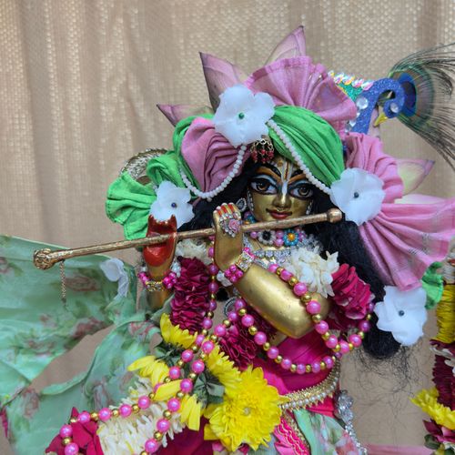 Free Colorful statue of a Hindu deity adorned with flowers and playing a flute. Perfect blend of culture and art. Stock Photo