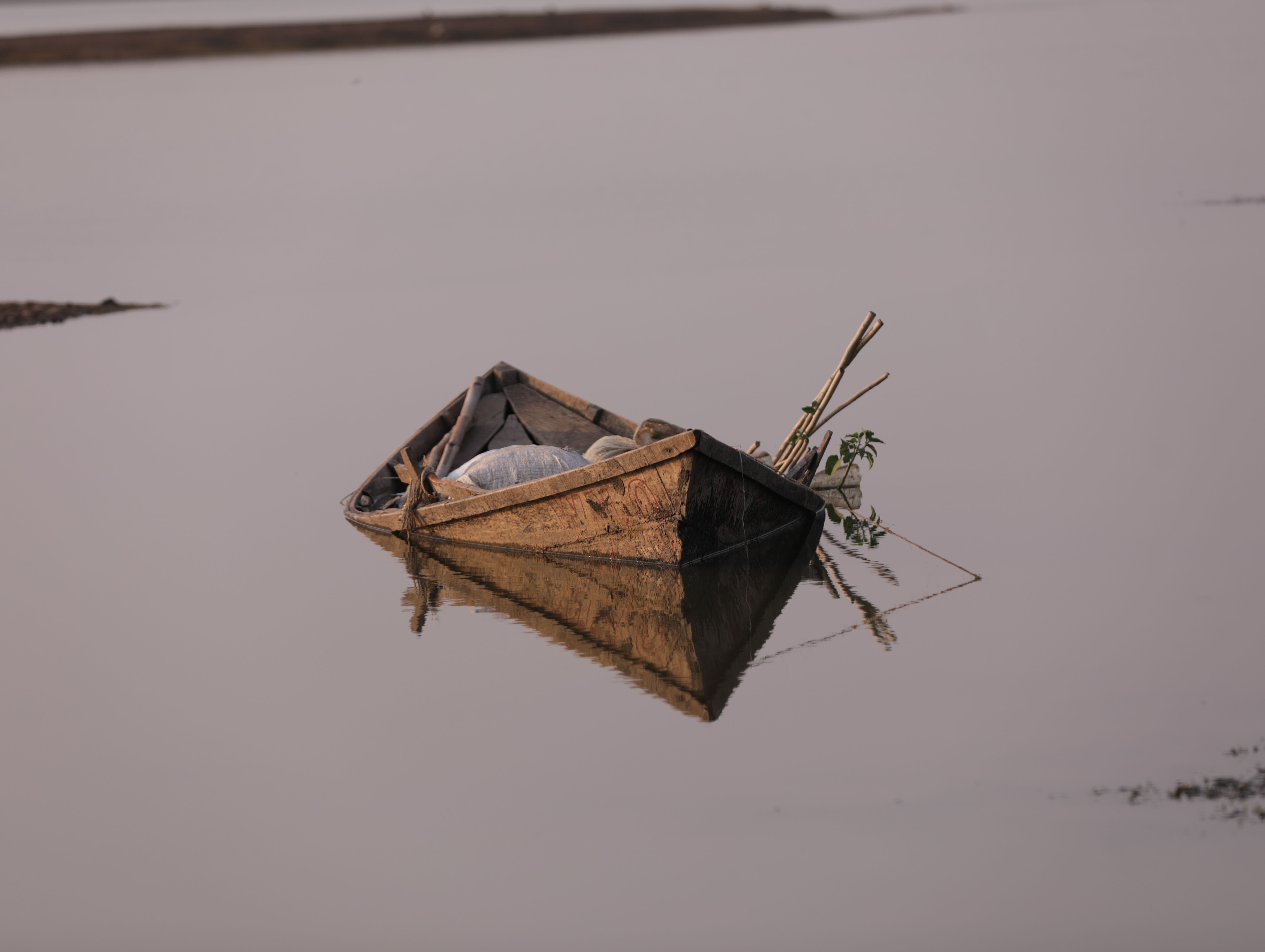 A tranquil scene of a wooden boat floating on still waters in India, reflecting tranquility and peace.