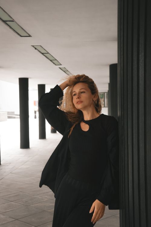 Free Elegant woman in black attire posing indoors with modern architecture background. Stock Photo