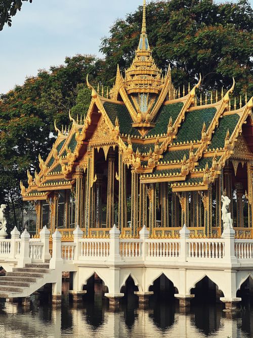 Free Beautiful Thai pavilion architecture with intricate details reflected in tranquil waters, surrounded by lush greenery. Stock Photo