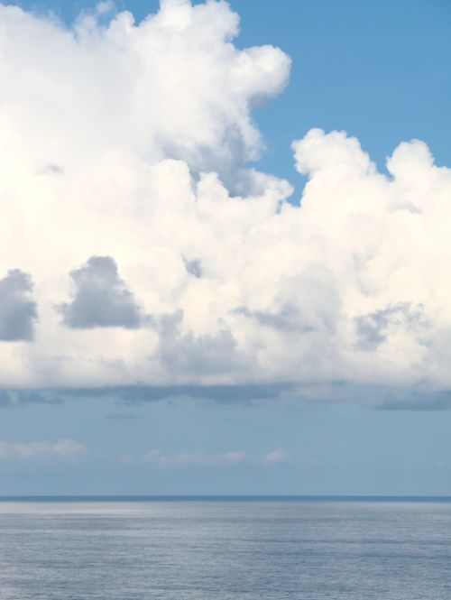 Free Serene seascape with blue sky and fluffy clouds at the horizon. Stock Photo
