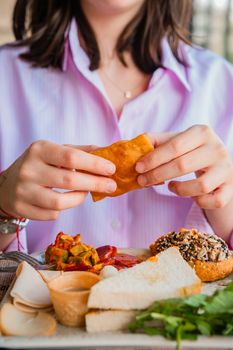 Close-up of a person enjoying a fresh brunch with various dishes and bread.