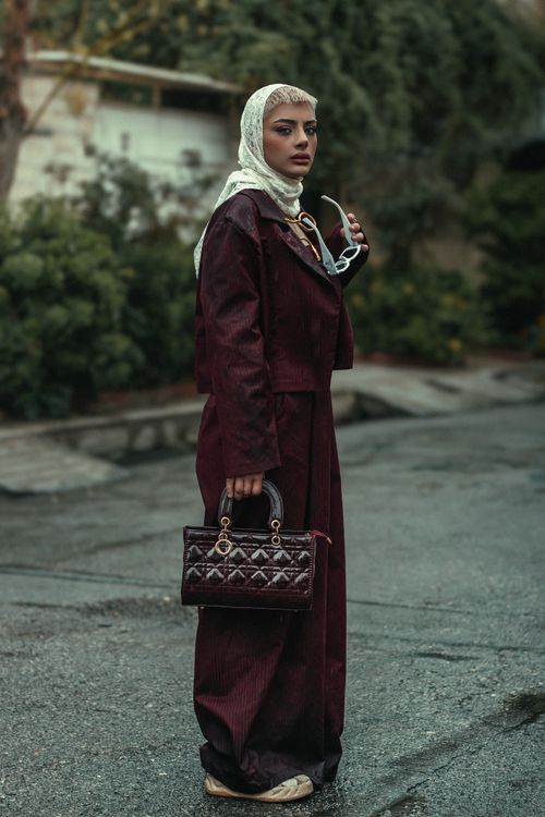 Free Elegant woman with headscarf holding sunglasses and handbag outdoors. Stock Photo