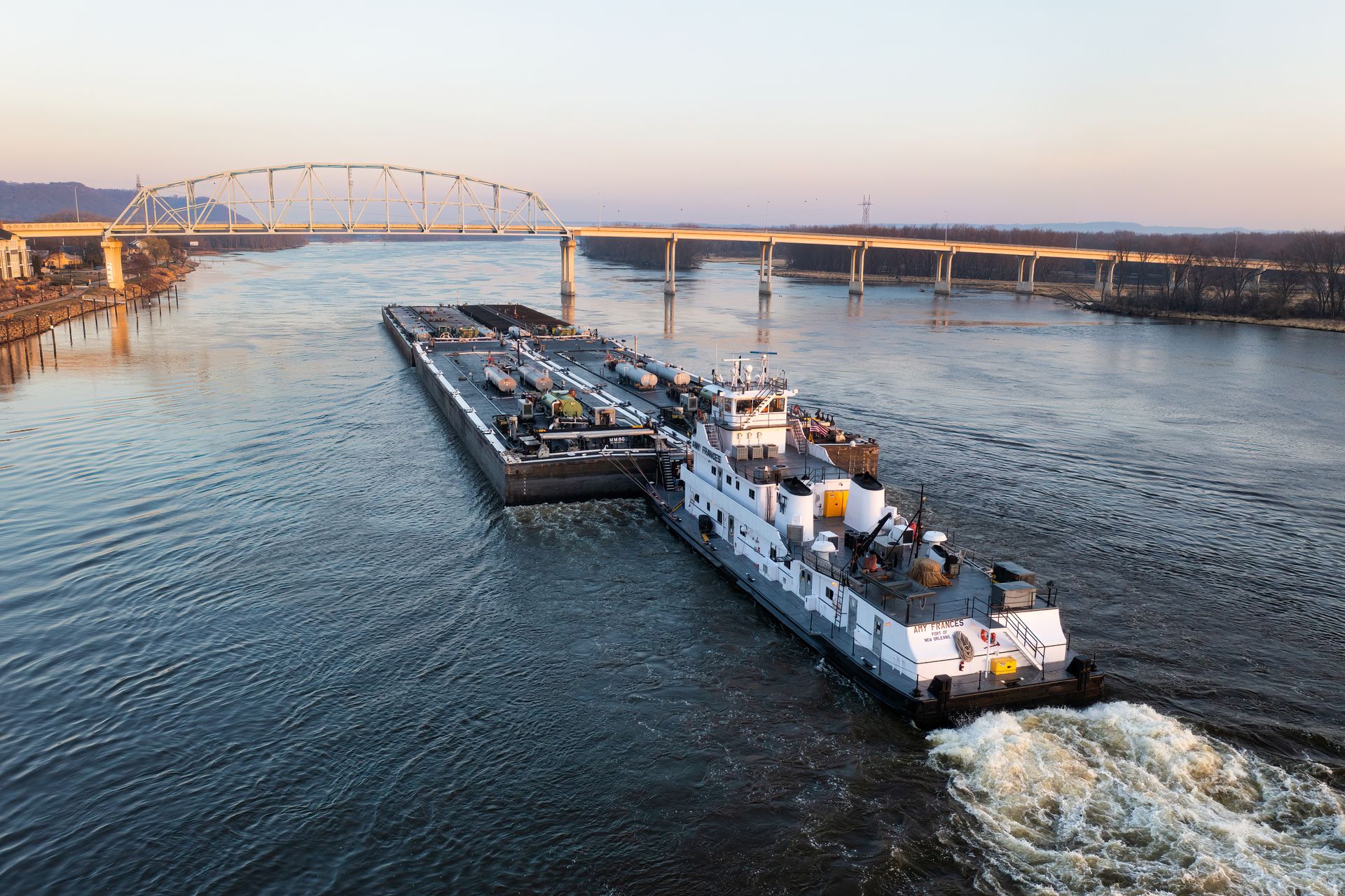 A barge navigates the Mississippi River near Wabasha, Minnesota with the Highway 60 Bridge in the background.
