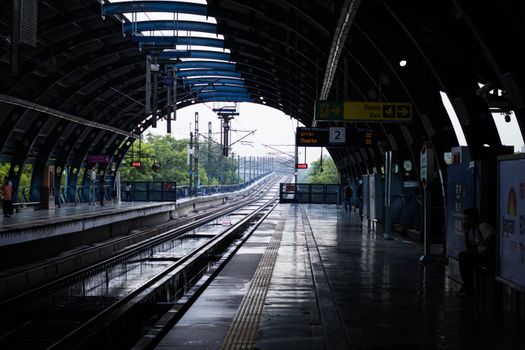 A quiet afternoon at a New Delhi metro station with wet tracks post rain, reflecting urban life.