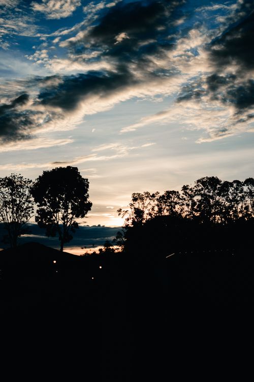 Free A captivating sunset with silhouette trees and dramatic clouds in the Philippines. Stock Photo