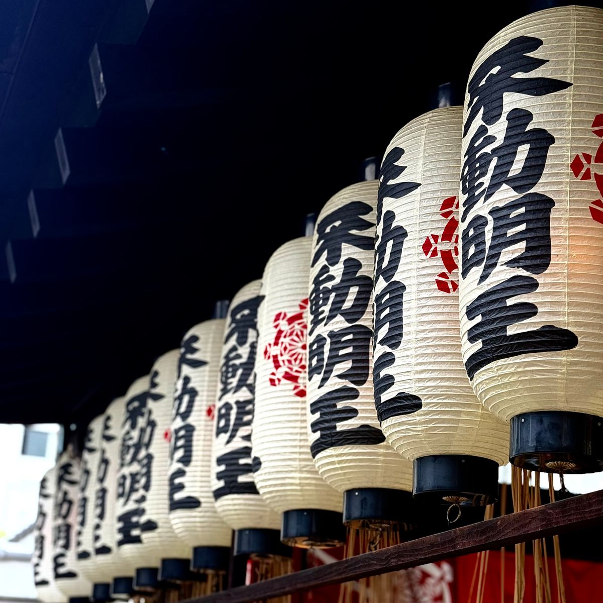 Row of traditional Japanese paper lanterns with calligraphy glowing in the dark