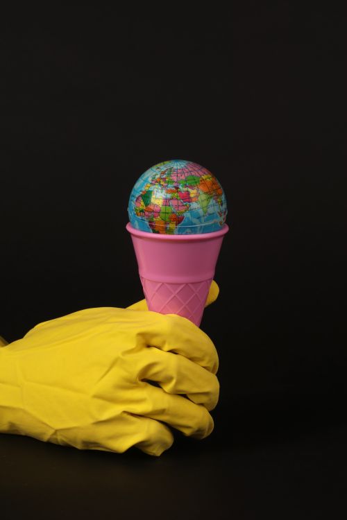 Free Creative concept of Earth globe in a pink ice cream cone held by gloves. Stock Photo