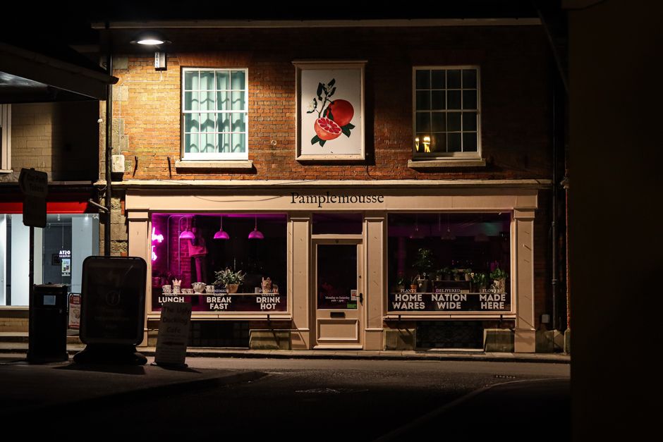 A cozy evening view of a lit shopfront in Shaftesbury, England, showcasing the charm of a nighttime street.