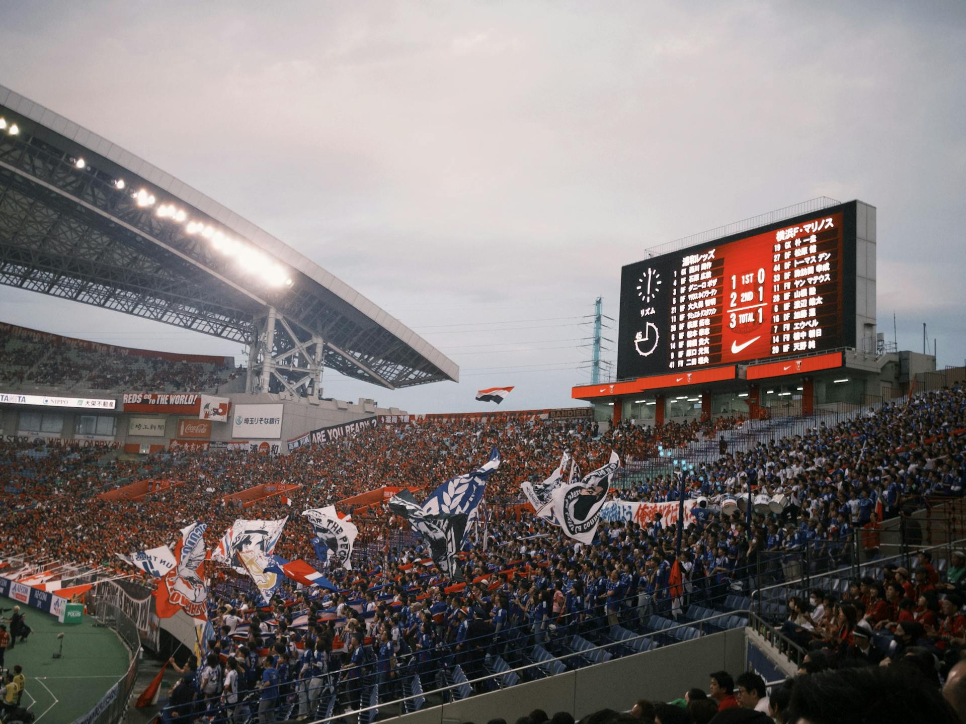 A lively soccer stadium scene with fans waving flags and a scoreboard displaying match details.