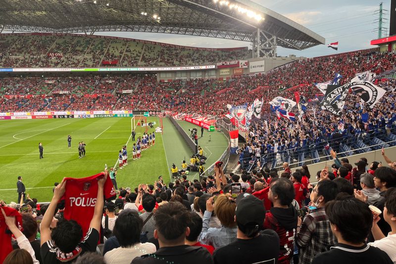 A thrilling soccer match at a packed stadium with energetic fans waving flags and cheering in Japan.