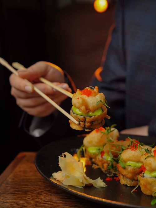 Free Close-up of gourmet sushi being held with chopsticks, emphasizing culinary art. Stock Photo
