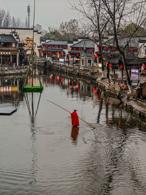 Free Scenic view of a historic town with a canal, traditional architecture, and red lanterns reflecting on the water. Stock Photo