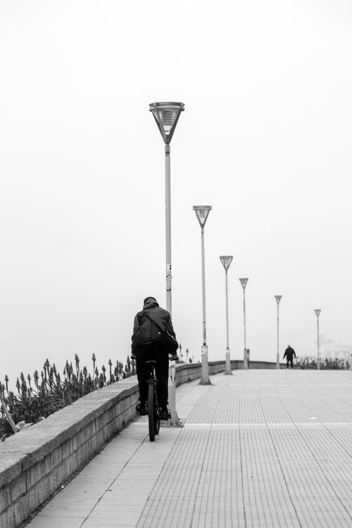Free Person cycling along a foggy waterfront promenade in Mar del Plata, Argentina. Stock Photo