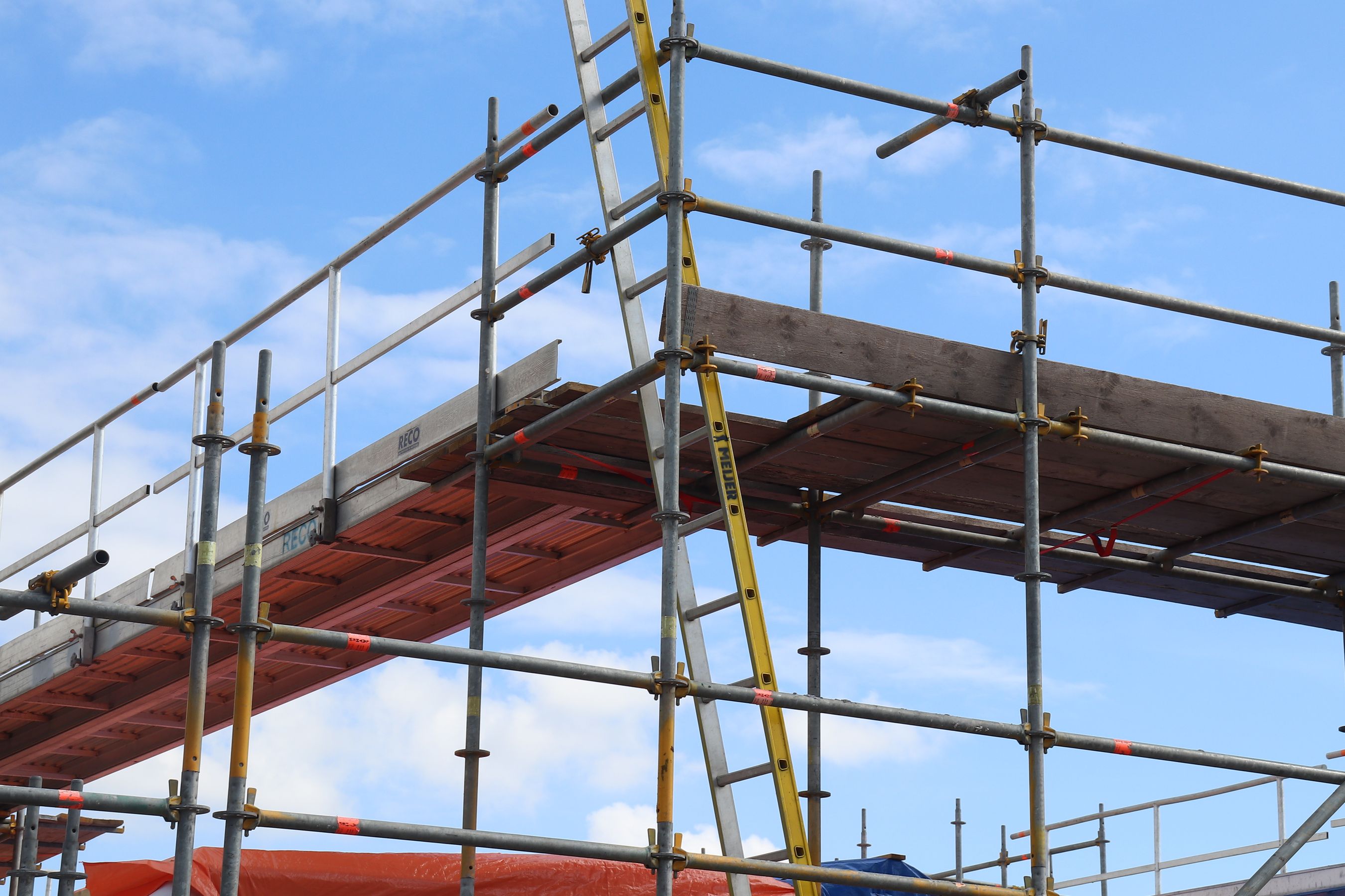 Construction scaffolding and ladder against a bright blue sky